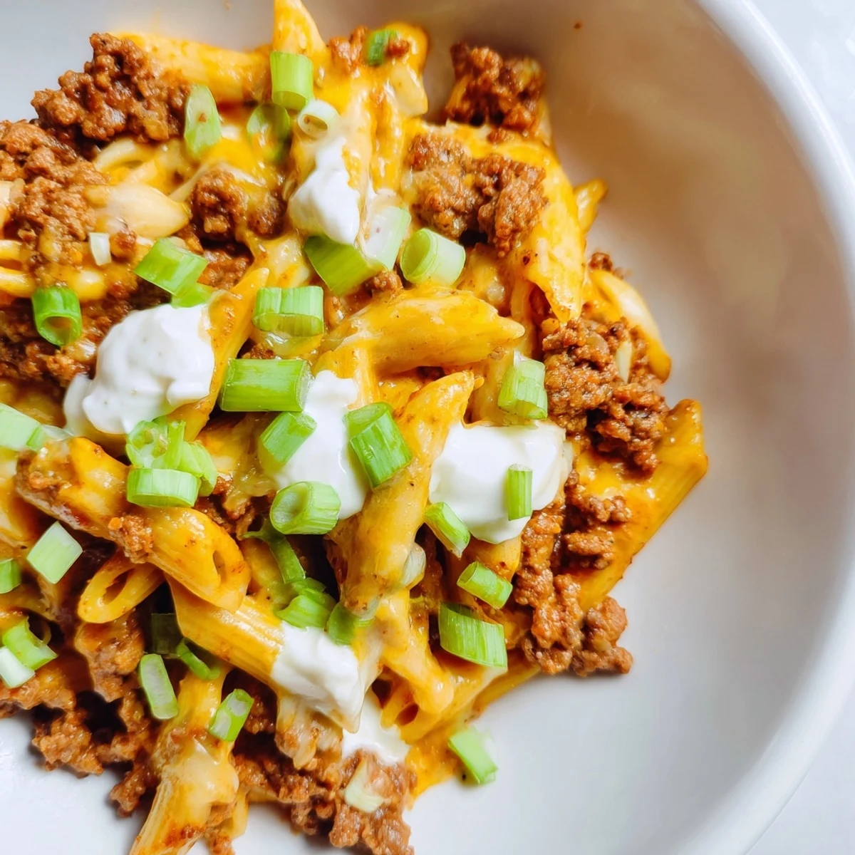 This photo shows a comforting bowl of One-Pot Taco Pasta steaming, with melted cheese and fresh herbs.