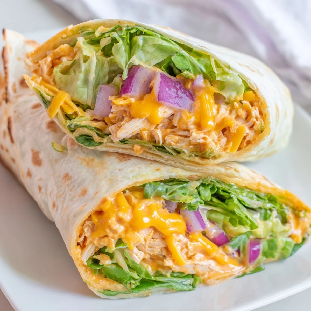 Golden-brown Buffalo Ranch Chicken Wraps rest on a rustic wooden cutting board, drizzled with creamy ranch dressing and extra buffalo sauce for a tangy, spicy kick perfect for an easy American dinner.