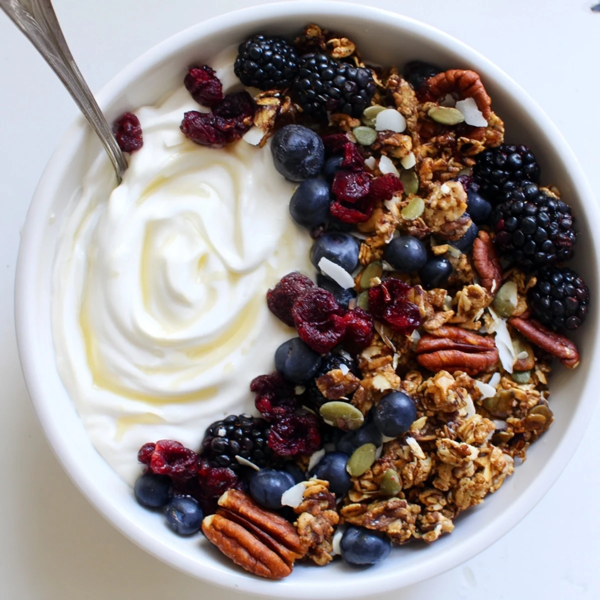 Served in a rustic bowl, this gluten-free yogurt breakfast features maple-kissed crunch and bright pomegranate and blackberry toppings.