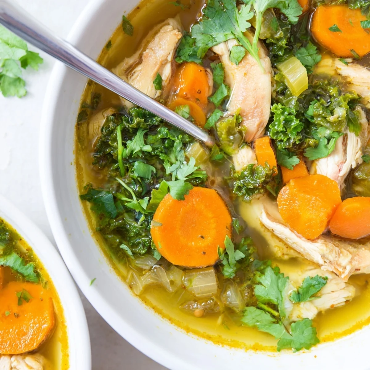 Steam rises from this nourishing Turmeric Chicken Soup, served alongside a slice of warm crusty bread for dipping.