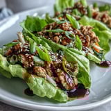 Freshly cooked Turkey Potsticker Stir-Fry Lettuce Wraps are spooned into crisp, green butter lettuce cups, garnished with toasted sesame seeds.