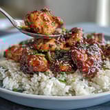2. Slow-cooked Honey Garlic Chicken with Rice: juicy chicken thighs glazed in savory honey garlic sauce, plated with steaming rice.  