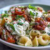 Golden garlic and ripe tomatoes infuse olive oil, creating a silky sauce for this Caprese pasta with burrata.  