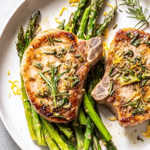 Golden seared One-Pan Lemon Herb Pork Chops with vibrant green asparagus, ready to be served.