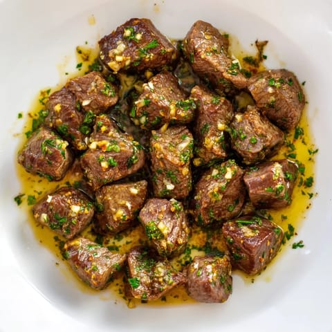 Golden, glistening Air-Fryer Garlic-Butter Steak Bites, ready to enjoy as a flavorful appetizer with lemon zest.