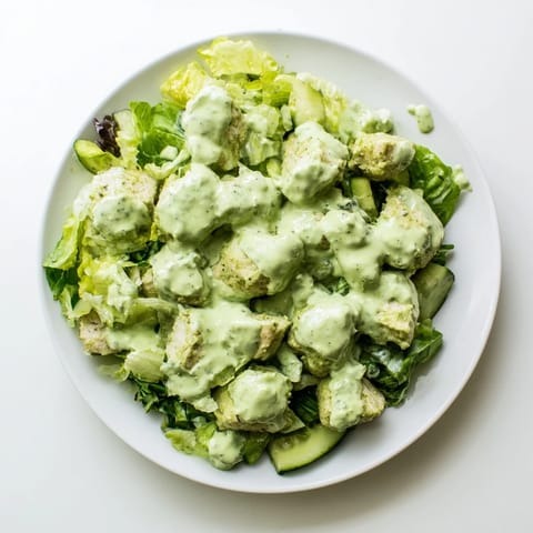 A close-up of Avocado Ranch Chicken Salad showing vibrant salad greens, halved tomatoes, and herbs garnishing the dish.  