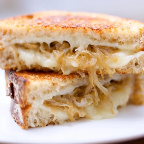 A close-up of the caramelized onion & Gruyère grilled cheese shows the melted cheese oozing from crispy, golden-brown bread.