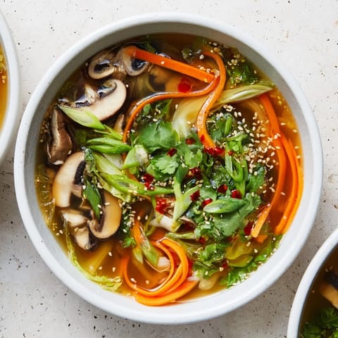 Spoon lifting vibrant vegetables and silken tofu from the aromatic ginger-miso broth in a rustic ceramic bowl.  