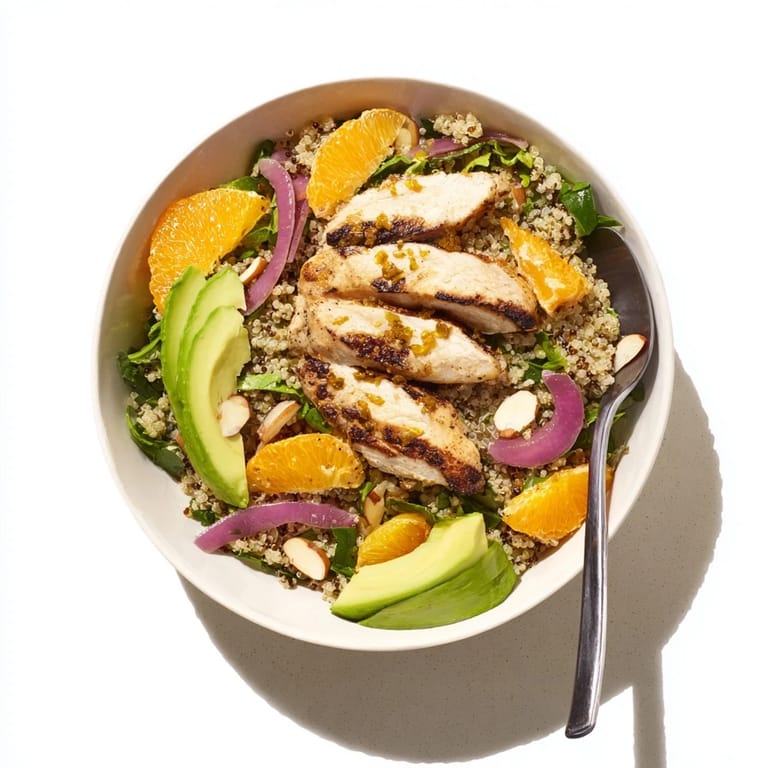 A bed of mixed greens and warm quinoa supports sliced grilled chicken in the vibrant Citrus Herb Chicken Salad Bowl, finished with a bright citrus dressing.
