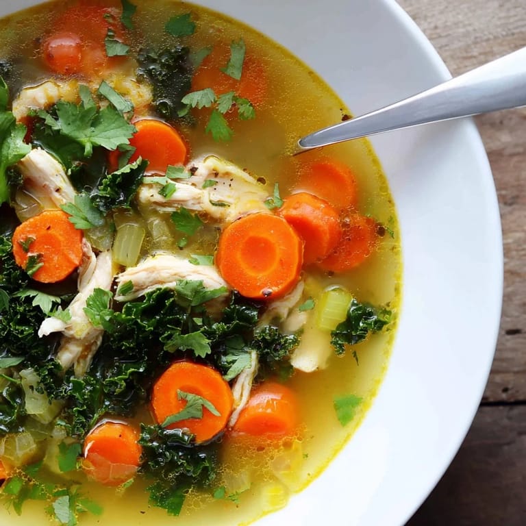 Colorful carrots and celery float in this bright yellow Turmeric Chicken Soup, highlighting its aromatic and wholesome ingredients.