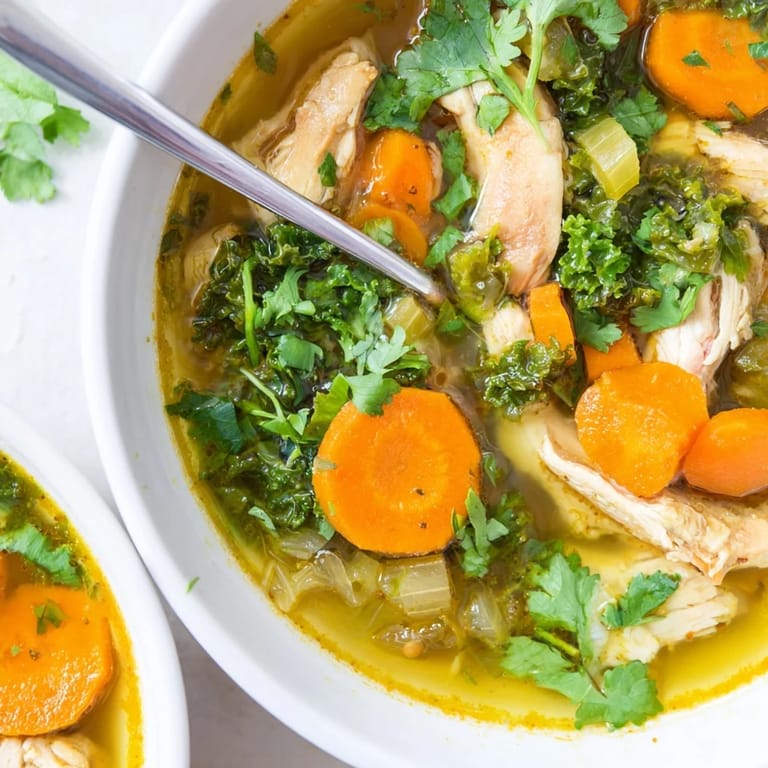 Steam rises from this nourishing Turmeric Chicken Soup, served alongside a slice of warm crusty bread for dipping.