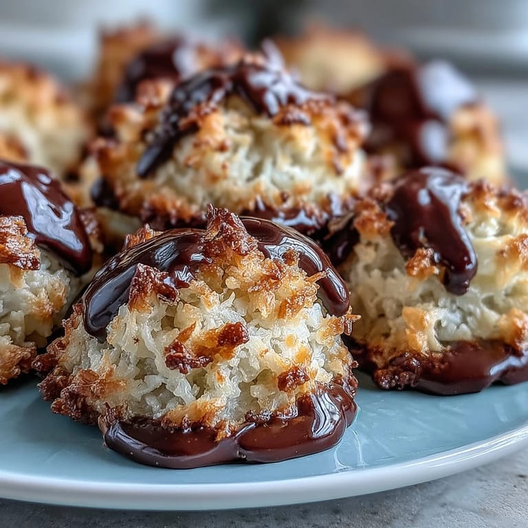 Chewy, golden coconut macaroons with a glossy dark chocolate drizzle, offering a naturally sweet and indulgent vegan treat.  